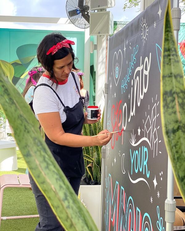 Andrea live painting the Step Into Your Magic mural