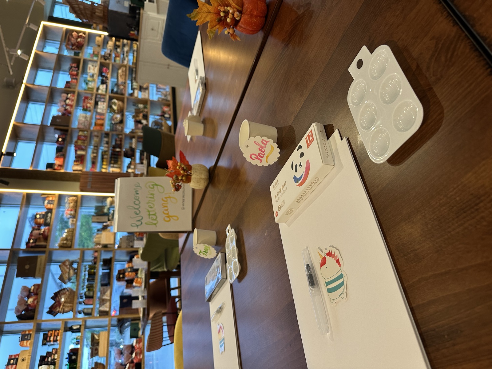 Workshop table set with practice paper, water brush pens, paint palettes and watercolor name tags before a brush lettering class in Miami